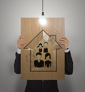 商务人士展示手画家庭和房屋的木海报 作为背景图片