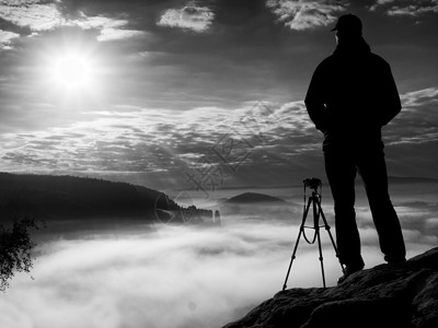 流年心情记录悬崖上的摄影师 自然摄影师在岩石峰顶用镜子相机拍照背景