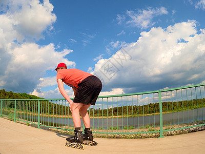 在桥上穿红T恤和黑裤子滑冰的内线滑冰机后视线高清图片