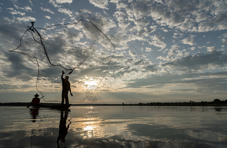 鱼轮廓渔民在W日落时扔鱼网钓鱼的休光灯蓝色天空生活渔夫太阳男人瓦农橙子背景