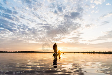 渔民在W日落时扔鱼网钓鱼的休光灯天空渔夫橙子瓦农太阳蓝色生活男人背景