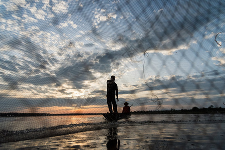 洛瓦特网渔民在W日落时扔鱼网钓鱼的休光灯男人太阳蓝色天空生活瓦农橙子渔夫背景