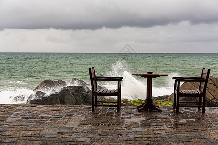 浪沙在弃置桌旁海岸岩石上坠毁的纳里海浪异国海岸线进口泡沫热带天空蓝色休息室椅子支撑背景