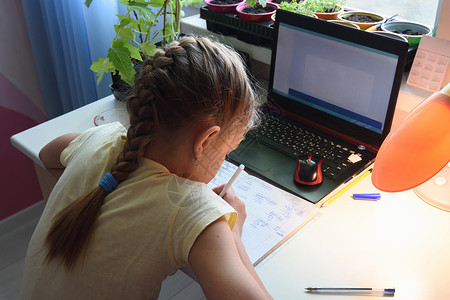 女孩在笔记本电脑前用笔记本解决数学范例高清图片