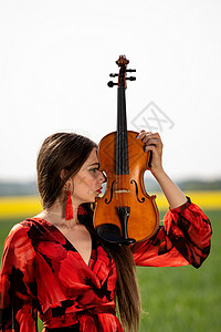 小提琴琴颈一个积极的年轻女子的画像 部分脸被小提琴的琴颈遮住了女孩音乐家娱乐小提琴家青少年黑发女士细绳艺术创造力背景