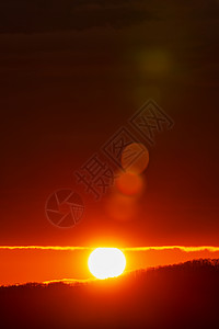 太阳在山上升起 红色日光碟从山脉顶端升起 橙色天空中美丽的天然透镜照明弹背景图片