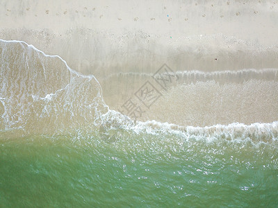 透明青蓝色海浪在清洁沙沙滩上的蓝海浪太阳天空支撑日落海岸线天线飞溅假期晴天旅游背景