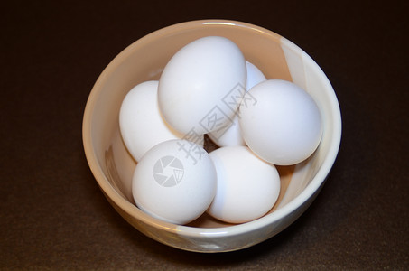 相比位于黑暗背景的两色碗中的白鸡蛋 黑底面背景