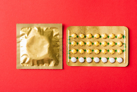 红色避孕套包装包装袋和避孕药丸上的安全套和荷尔蒙泡泡教育药物怀孕控制口服女性避孕制药药品排卵背景