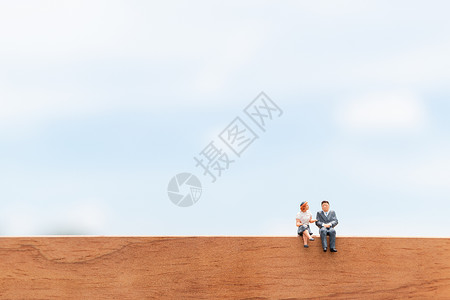 商业人士坐在蓝色天空背景的木地板上 坐着蓝天背景背景图片