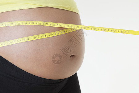 在白色背景下用胶带测量胃部的孕妇中产剖口成年女性数字影棚裁剪怀孕卷尺腹部成人孕产背景图片