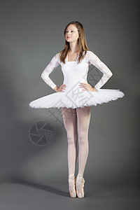年轻女性芭蕾舞女舞蹈家在灰色背景下低步跳脚高清图片