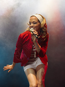 唱歌名人表演女性在舞台音乐会中歌唱 在低角度的观众面前名人明星短发享受音乐成人手臂流行音乐摇滚歌手背景