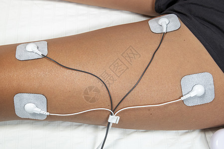 ems妇女在家里使用TENS和EMS机器 在其中一名男子的肌肉上皮肤技术刺激病人女性治疗电气神经电极震惊背景
