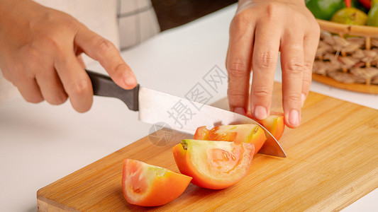 西红柿片女人把新鲜番茄切成碎片 用刀砍木头背景