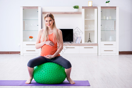 瑜伽瑞士球准备在家中进行节育的年轻女性微笑卫生女士肚子健身保健姿势身体瑜伽训练背景