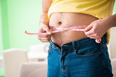 锯腹脂鲤在饮食概念中用胶带量度衡量人体脂肪的人肚子食物损失大腹营养磁带身体男人腹部仪表背景