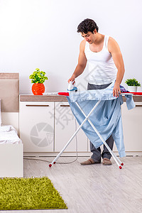 床布年轻人在卧室熨衣服男人家庭主妇器具外包房间木板打扫丈夫家庭清洁工背景
