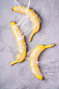 卖包文字素材在石块混凝土上包装成塑料包裹的香蕉水果背景