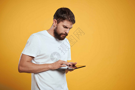 在白色T恤衫上用黄色背景的平板牌男子 商务人士触摸屏幕触摸板的新科技展示快乐工作室衬衫商务商业工作人士软垫药片背景图片