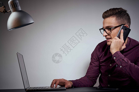 手戴眼镜和衬衫的商务人士坐在一张有开放式笔记本电脑的桌子上自由职业者工具博主设计师互联网人士工作室市场网络职业背景图片