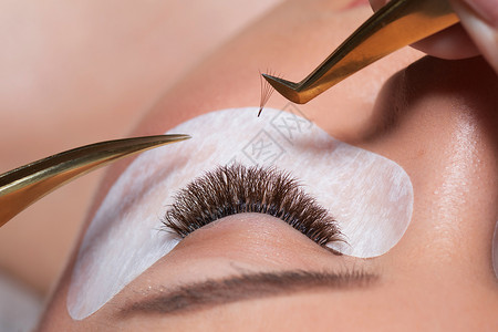 眼电击延伸程序 在tweezers准备的假鞭笞女士女性化妆品补丁沙龙眼睛镊子女孩治疗背景