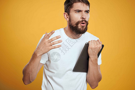 在白色T恤衫上用黄色背景的平板牌男子 商务人士触摸屏幕触摸板的新科技人士触摸屏工人成人工作室软垫商业展示成功办公室背景图片