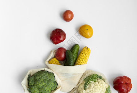 装玉米白色表面生态袋中的蔬菜 胡椒 西红柿 玉米 黄瓜 西兰花 花椰菜 装在可重复使用的购物环保棉布袋中 零废物和无塑料概念 可持续的背景