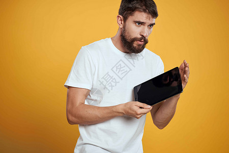 在白色T恤衫上用黄色背景的平板牌男子 商务人士触摸屏幕触摸板的新科技成人男性男人办公室触摸屏工作衬衫工作室互联网商务背景图片