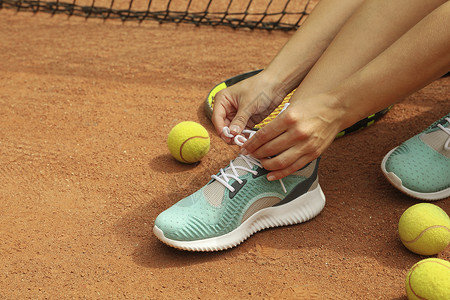 搭售妇女用电击球和网球在粘土场上系鞋带竞赛游戏玩家黏土篮子活力运动运动鞋球拍娱乐背景