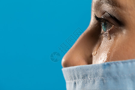 医疗事故一位年轻的女医生在失去一名长期治疗的感染COVID19的病人后正在哭泣蓝色疾病病房面具服务背景悲伤女子医院预防背景