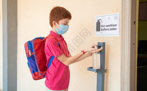 开学爆到儿童在进入教室前 先用手洗净剂使用医疗面具 即返回学校或重新开学的概念和冠状病毒或共生19号安全措施卫生学生消毒剂书包教育孩子们背景