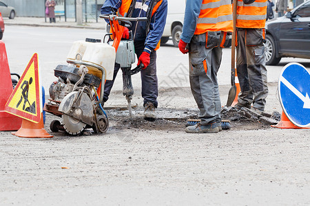 一组公路工人用电动大锤 切油机 铲子和刷子修理了一段路段背景