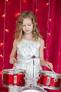 笑笑的小女孩在红背景的鼓上打鼓 与新年花冠盒子女孩小姑娘季节工作室假期快乐女士庆典微笑背景图片
