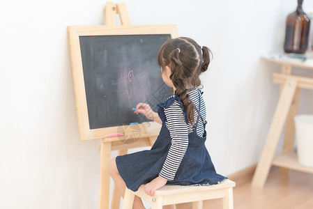 黑板漫画快乐的亚洲女孩在黑板上用粉笔画漫画 在家里学习幼儿园作业童年知识绘画教育乐趣微笑卡通片学生背景