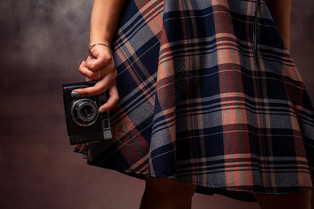 女孩的手握着摄像头 在衣服的发热 摄影棚摄影工作室拍摄 灰色背景背景图片