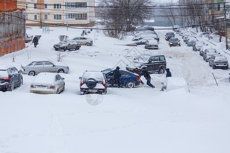 索拉里斯两人将卡住的现代太阳能汽车推入山坡深雪中停泊在停车场之间的一个雪院车辆帮助雪堆运输邻居季节暴风雪气候天气男人背景