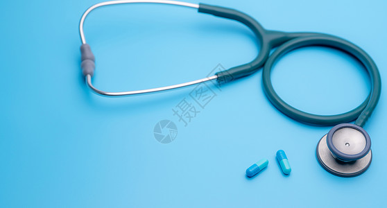 汀蓝色胶囊药丸和蓝色背景上的绿色听诊器 健康检查 用于心跳测试的心脏病学医生设备 医疗保健和医疗概念 用于诊断的诊断医疗工具抗菌剂背景