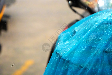 摩托车雨衣雨中蓝色雨衣上的雨滴被扔到滑板车上的特写摩托车人群天气塑料摩托雨披倾盆大雨下雨行人运输背景