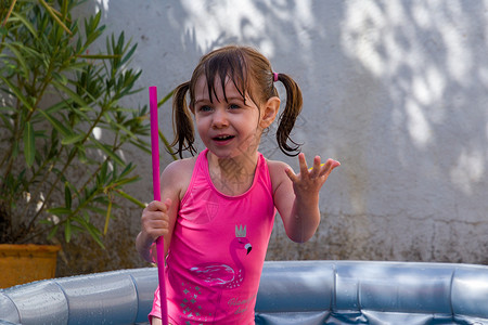 刘海戏金蟾在游泳池里穿粉红色泳衣的宝贝女孩背景