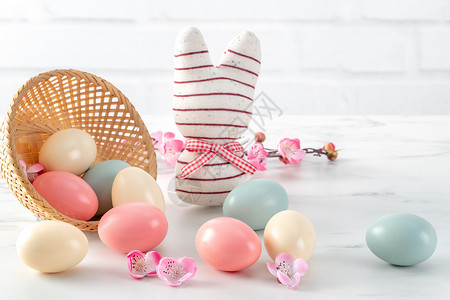 充满疑问的兔子鸟巢里有粉红羽花的彩色复活节鸡蛋桌子假期木头李子庆典兔子卡片乐趣篮子玩具背景