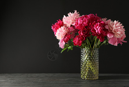 玻璃花瓶粉色花玻璃花瓶 木桌上有一束美丽的牡丹花 黑色背景空间为 tex背景