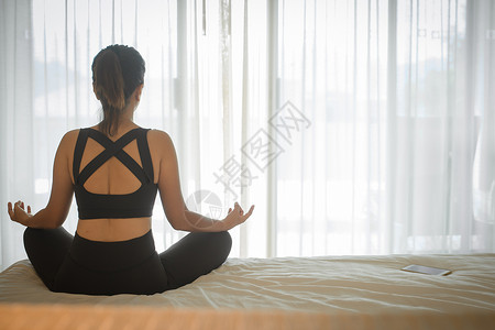做床上妇女在家里床上做瑜伽锻炼 在卧室早间锻炼 健康和体育生活方式背景