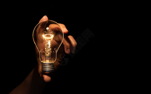 手持灯泡 在黑色背景中被隔绝 能源或思想概念高清图片