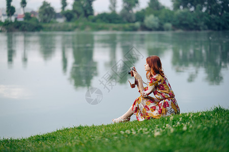 请保持安静在湖边度假的岸边 女人穿着衣服外出 手里拿着照相机背景