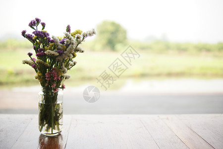 在庭院玻璃花瓶中的花朵桌子花束露台装饰植物群瓶子风格背景图片