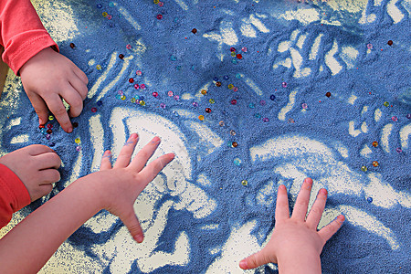 手机动素材儿童双手在白桌沙沙疗法上触摸蓝色沙子 发展精巧的机动技能背景