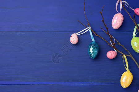 挂蛋装饰性复活节彩蛋挂在树枝上蓝色木质背景背景