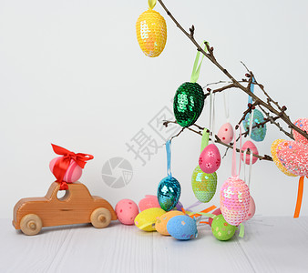 带有粉色复活节蛋的木制玩具车 用红色丝带固定装饰传统玩具庆典季节风格绿色娃娃季节性白色背景图片