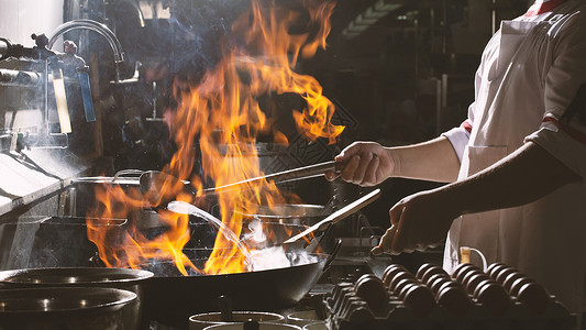 厨师在厨房忙着做饭餐具调子运动平底锅烧伤机器蔬菜油炸食物火炉背景图片